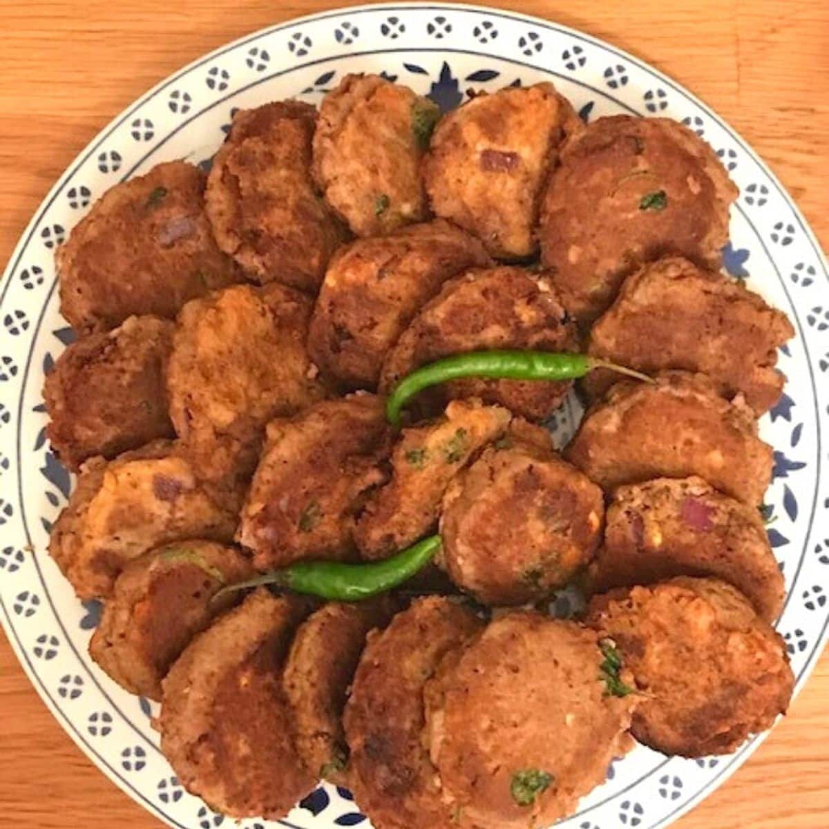 A plate of golden-brown Shami Kebabs, ready to be served.